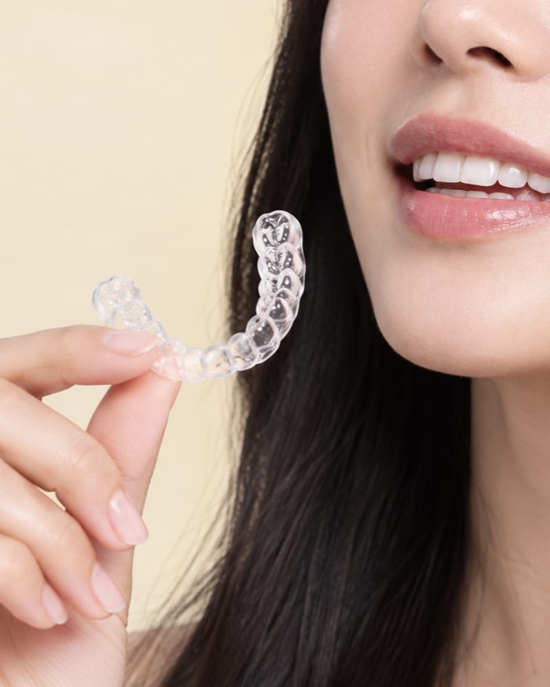Close-up of a patient fitting a clear aligner over her upper teeth